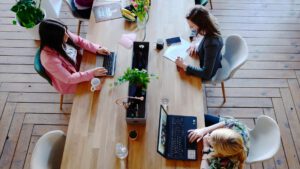 Three women working at a communal table.